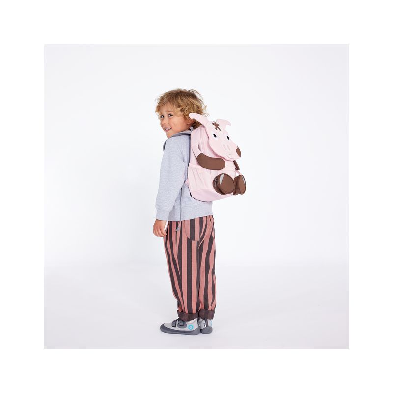 Ein Kind mit grauem Hoodie, gestreifter Hose und pinkem Tier-Rucksack lächelt in die Kamera. Ein Kind mit grauem Hoodie, gestreifter Hose und pinkem Tier-Rucksack lächelt in die Kamera.