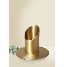 Messing-Stifthalter mit schräger Oberseite auf rundem Sockel, daneben einige grüne Blätter.