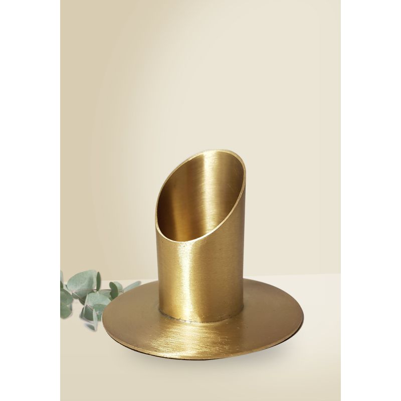 Messing-Stifthalter mit schräger Oberseite auf rundem Sockel, daneben einige grüne Blätter. Messing-Stifthalter mit schräger Oberseite auf rundem Sockel, daneben einige grüne Blätter.