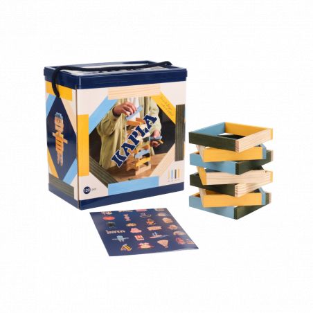 Kapla-Holzbauklötze in einer Box mit Anleitung, daneben gestapelte bunte Planken.