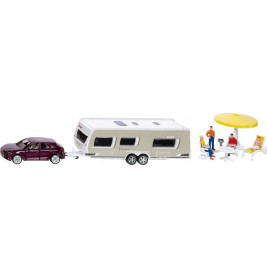 Spielzeugauto zieht Wohnwagen an, daneben sitzen Miniaturfiguren unter einem gelben Sonnenschirm.