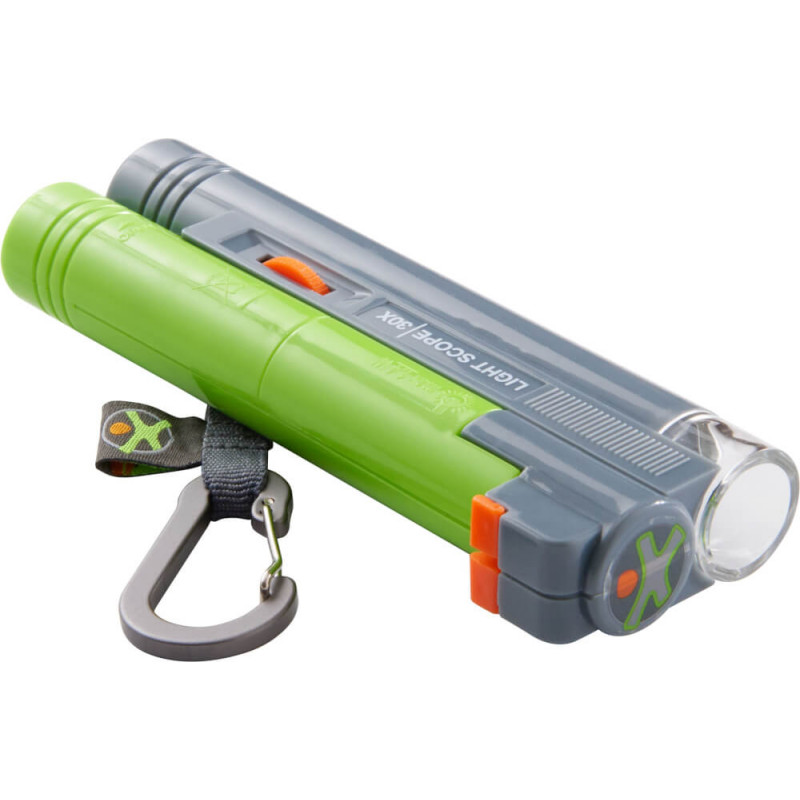 Grün-graue Taschenlampe mit Karabiner und orangenen Akzenten liegt auf weißem Hintergrund.