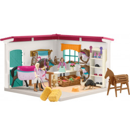 Spielzeug-Pferdestallset mit Figuren, Pferden, Hund, Heuballen und Zubehör in einer Ecke des Raums.