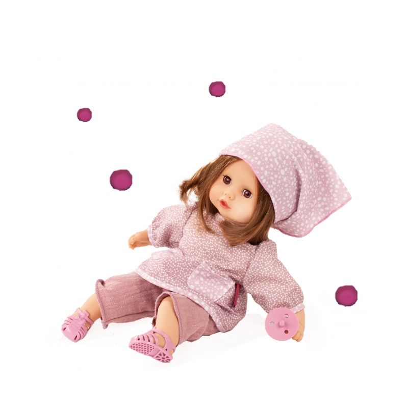 Eine Puppe mit braunen Haaren trägt rosa Kleidung und Mütze, sitzt mit rosa Spielzeug und rosa Punkten um sie herum.