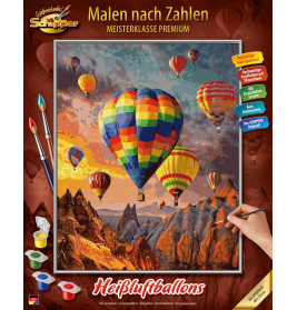 Eine Hand malt eine bunte Heißluftballonszene über Bergen, unten sind Farbtöpfe und Pinsel zu sehen.