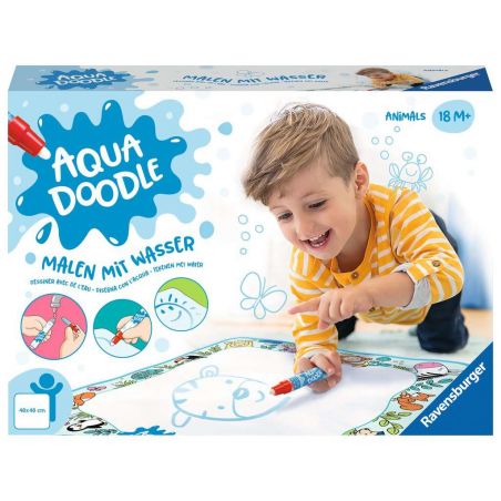 Ein Junge malt lächelnd mit einem Wasserstift auf einer Aqua Doodle Matte an einem Tisch.