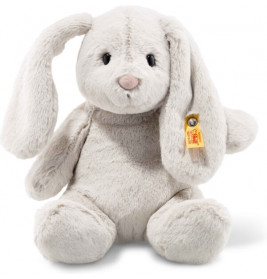 Ein weiches, hellgraues Plüschhäschen mit langen Schlappohren und gelbem Etikett am linken Ohr.