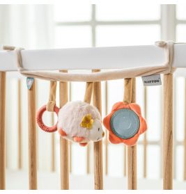 Weiches Babybett-Spielzeug mit Plüschigel, orangenem Ring und Blumen-Spiegel am Gitter hängend.