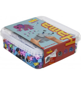 Eine Plastikbox mit bunten Hama-Perlen, darauf bastelt ein Kind mit den Perlen ein Motiv auf dem Deckel.