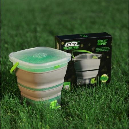 Klappbarer Behälter mit Gelperlen auf Gras neben schwarz-grüner Gel Blaster Gelet Depot Verpackung.