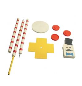 Spielzeuge: gestreifte Stäbe, gelbes Kreuz, rote Scheiben, weißer Kreis und ein Block mit Gesicht und Zylinder.