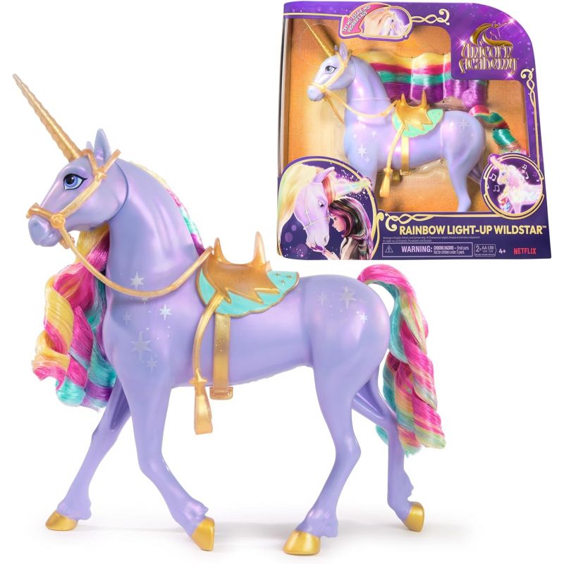Ein lila Einhornspielzeug mit Regenbogenmähne, goldenem Horn und Sattel steht neben seiner bunten Verpackung. Ein lila Einhornspielzeug mit Regenbogenmähne, goldenem Horn und Sattel steht neben seiner bunten Verpackung.