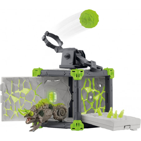 Ein Spielzeug-Dinosaurier kommt aus einer aufgebrochenen grau-grünen Box, während ein grünes Geschoss abgeschossen wird.