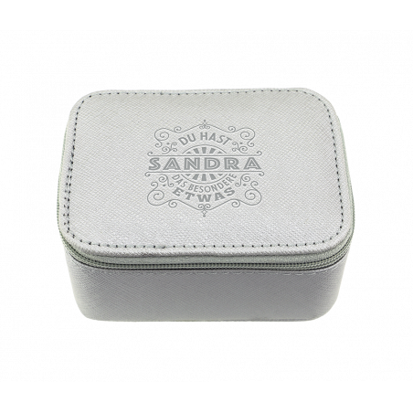 Hellgraue, rechteckige Box mit Reißverschluss und dem Aufdruck Sandra sowie Ziertext auf dem Deckel.