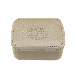 Beiges Etui mit Reißverschluss und geprägtem Text SILVIA SEI DIE HELDIN IN DEINEM EIGENEN ABENTEUER auf dem Deckel.
