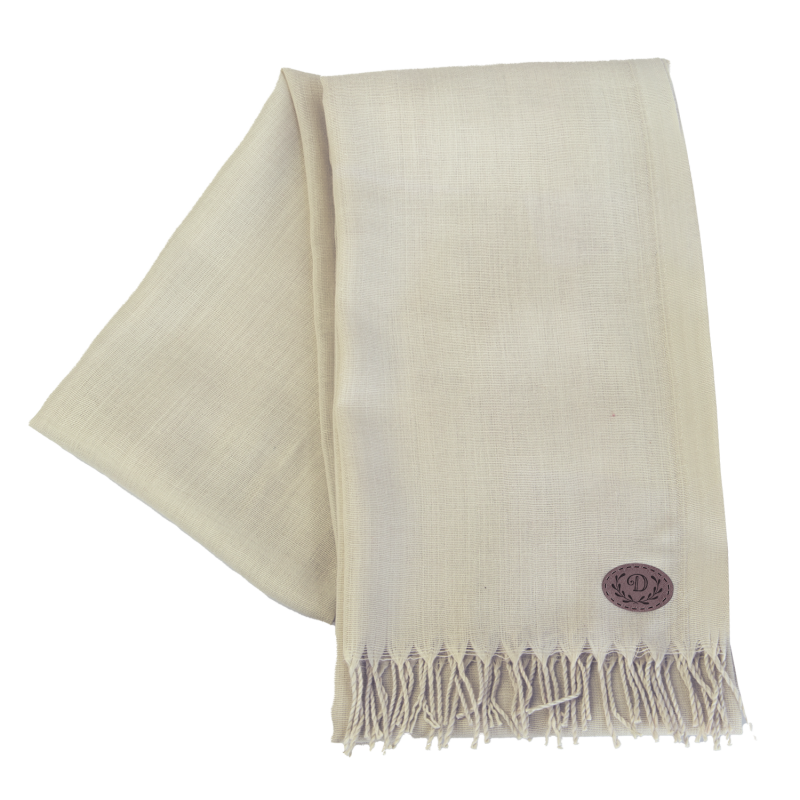 Beiger Schal mit Fransen und einem kleinen, runden braunen Logoaufnäher in einer Ecke. Beiger Schal mit Fransen und einem kleinen, runden braunen Logoaufnäher in einer Ecke.