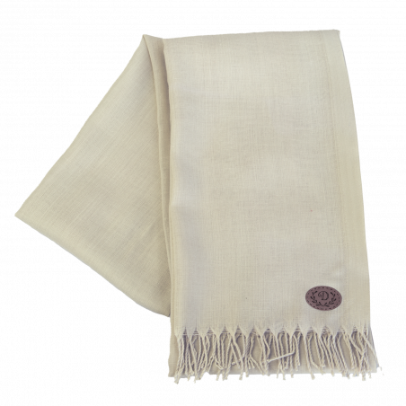 Beiger Schal mit Fransen und einem kleinen, runden braunen Logoaufnäher in einer Ecke. Beiger Schal mit Fransen und einem kleinen, runden braunen Logoaufnäher in einer Ecke.