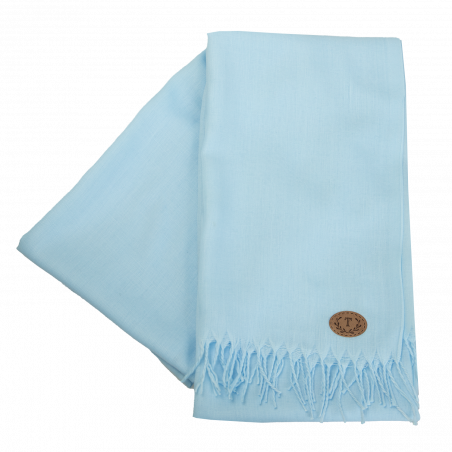 Hellblauer Schal mit Fransen und kleinem ovalen, braunen Aufnäher mit dekorativen Initialen.