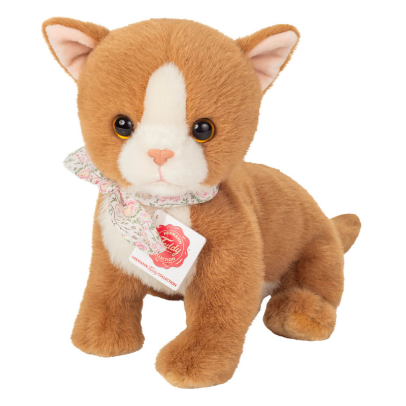 Eine orange-weiße Plüschkatze mit Blumenschal und Halsband sitzt aufrecht.