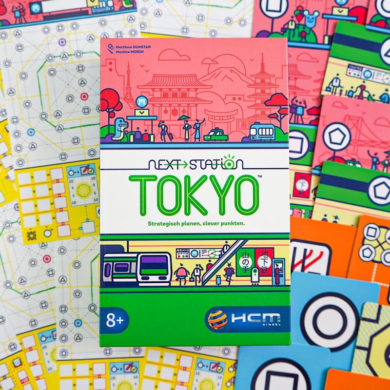 Die Next Station: Tokyo-Spielschachtel liegt auf bunten Spielbögen und Komponenten des Brettspiels. Die Next Station: Tokyo-Spielschachtel liegt auf bunten Spielbögen und Komponenten des Brettspiels.