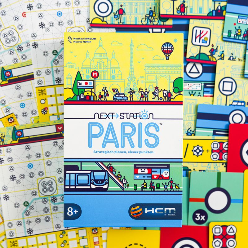 Die Schachtel von Next Station: Paris liegt auf bunten Spielkarten und Kartenblättern. Die Schachtel von Next Station: Paris liegt auf bunten Spielkarten und Kartenblättern.