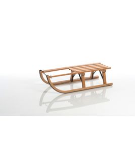 Ein Holzschlitten mit gebogenen Kufen steht auf einer weißen, reflektierenden Fläche.