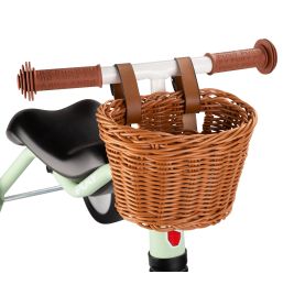 Nahaufnahme eines Kinderfahrrad-Lenkers mit braunem Weidenkorb, der vor dem Sitz befestigt ist.