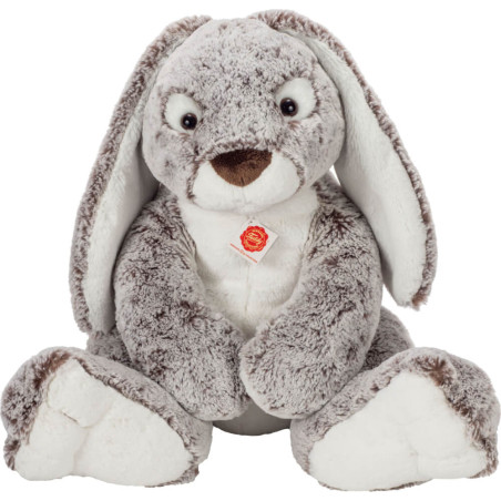 Grau-weißes Plüschkaninchen mit langen Ohren, sitzt aufrecht und trägt ein rot-goldenes Schild auf der Brust.