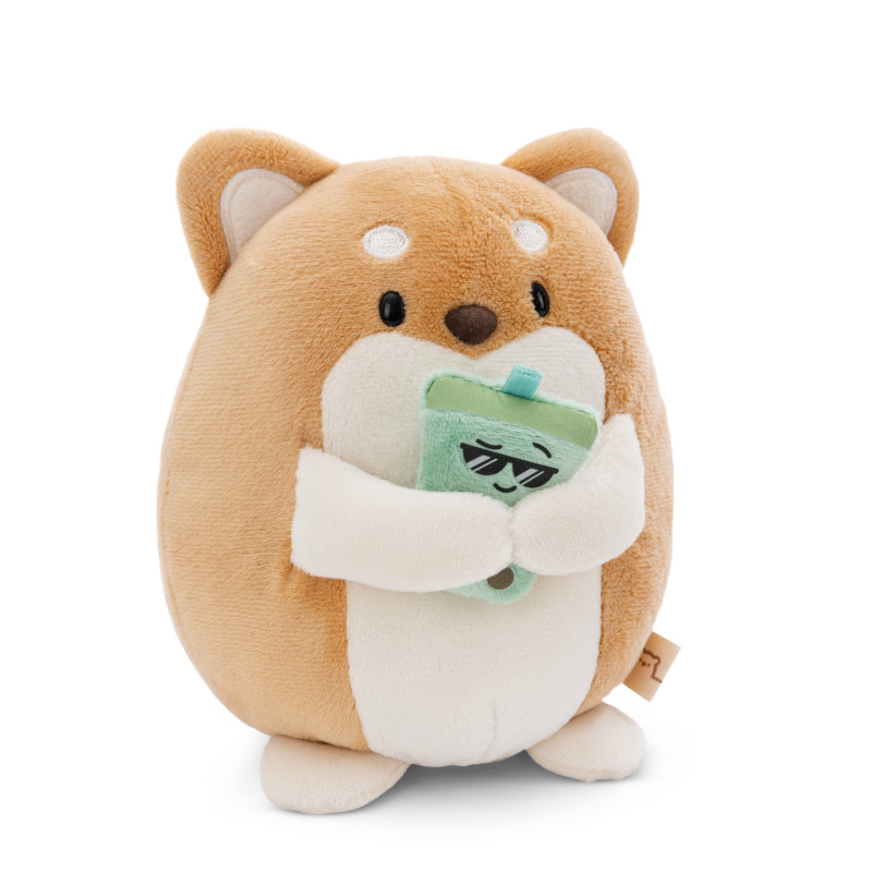 Stofftier eines rundlichen, beige-weißen Hundes mit grünem Getränkekarton und Strohhalm.