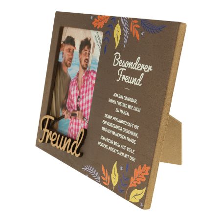 Holz-Bilderrahmen mit zwei Männern, deutschem Text und bunten Blättern am Rand.