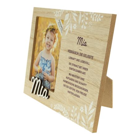 Holzrahmen mit Foto eines lächelnden Mädchens, Name Mia, Blumendeko und deutschem Text.