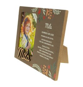 Brauner Bilderrahmen mit Blumenmuster, Foto eines Mädchens und Name Mila samt Beschreibung auf Deutsch.