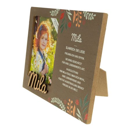 Brauner Bilderrahmen mit Blumenmuster, Foto eines Mädchens und Name Mila samt Beschreibung auf Deutsch.