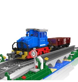 Blauer und roter Spielzeugzug mit Güterwagen aus Bausteinen fährt über eine Brücke, nahe einem 50er-Tempolimit-Schild.