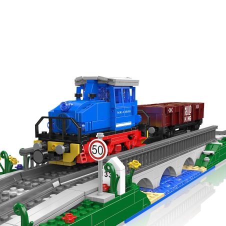 Blauer und roter Spielzeugzug mit Güterwagen aus Bausteinen fährt über eine Brücke, nahe einem 50er-Tempolimit-Schild.