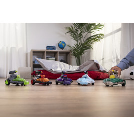 Fünf bunte Spielzeug-Monstertrucks stehen im Schlafzimmer auf dem Boden, eine Hand berührt einen Truck.