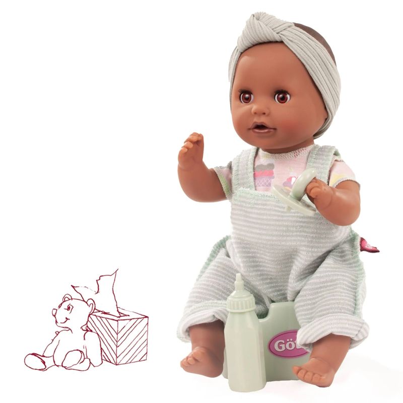 Eine Babypuppe in gestreifter Latzhose sitzt auf einem Töpfchen, daneben eine Flasche und eine Teddybärzeichnung.