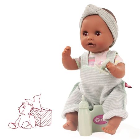 Eine Babypuppe in gestreifter Latzhose sitzt auf einem Töpfchen, daneben eine Flasche und eine Teddybärzeichnung.