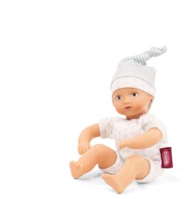 Babypuppe mit gestreifter Mütze und weißem Outfit mit rotem Etikett sitzt aufrecht vor weißem Hintergrund.