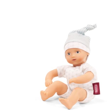 Babypuppe mit gestreifter Mütze und weißem Outfit mit rotem Etikett sitzt aufrecht vor weißem Hintergrund. Babypuppe mit gestreifter Mütze und weißem Outfit mit rotem Etikett sitzt aufrecht vor weißem Hintergrund.