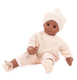 Eine braune Babypuppe mit cremefarbener Strickmütze, Pullover und rosa Hose sitzt aufrecht.