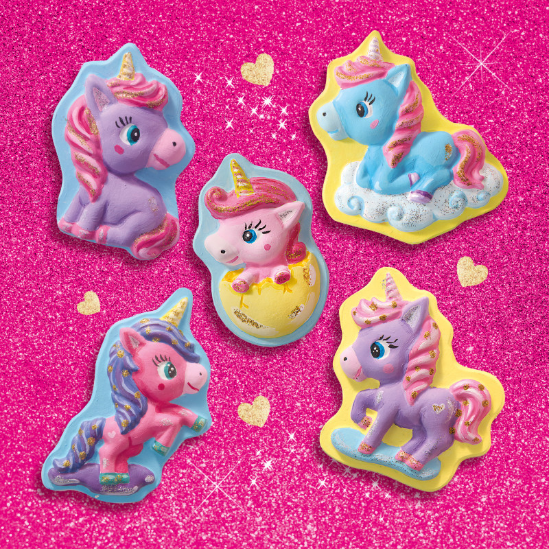 Fünf bunte Einhorn-Figuren auf glitzerndem, pinkem Hintergrund mit goldenen Herzen.