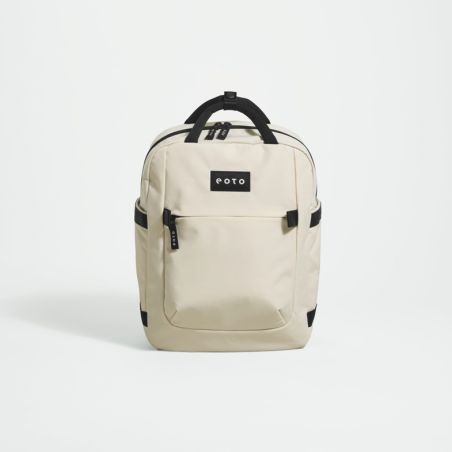 Cremefarbener Rucksack mit schwarzen Akzenten und Fronttasche steht aufrecht vor weißem Hintergrund.