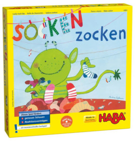 Ein grünes Monster sortiert Socken auf einer bunten Spielebox mit der Aufschrift Socken zocken von HABA.