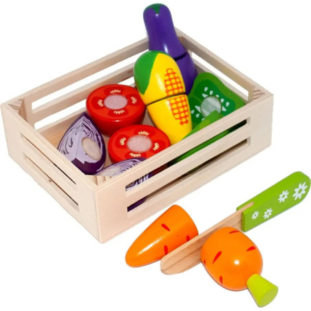 Holzkiste mit buntem Spielzeuggemüse, daneben liegen eine Spielzeugkarotte und ein Messer.