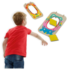 Junge wirft einen gelben Sitzsack auf ein buntes Wurfspiel mit Tiermotiven.