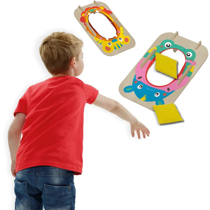 Junge wirft einen gelben Sitzsack auf ein buntes Wurfspiel mit Tiermotiven. Junge wirft einen gelben Sitzsack auf ein buntes Wurfspiel mit Tiermotiven.