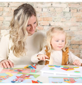 Eine Frau und ein Mädchen spielen am Tisch mit bunten Formen und Mustern.