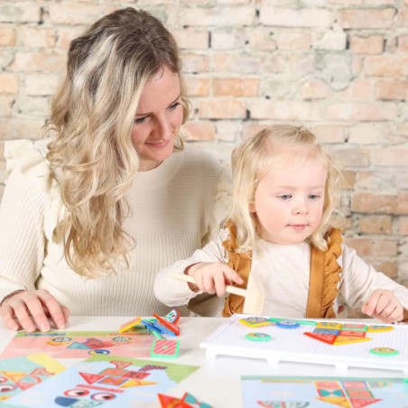 Eine Frau und ein Mädchen spielen am Tisch mit bunten Formen und Mustern. Eine Frau und ein Mädchen spielen am Tisch mit bunten Formen und Mustern.