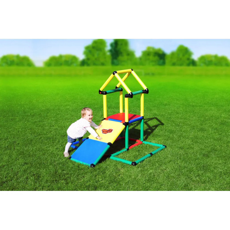 Ein Kleinkind spielt auf einem bunten Klettergerüst mit Rampen auf einer Wiese unter blauem Himmel. Ein Kleinkind spielt auf einem bunten Klettergerüst mit Rampen auf einer Wiese unter blauem Himmel.